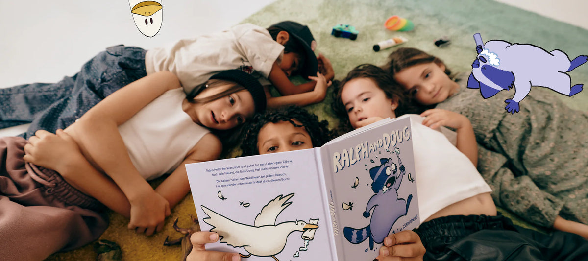 Fünf Kinder liegen auf einem Teppich und lesen gemeinsam im Buch Ralph and Doug, daneben schauen die gezeichneten Figuren Doug und Ralph ins Bild