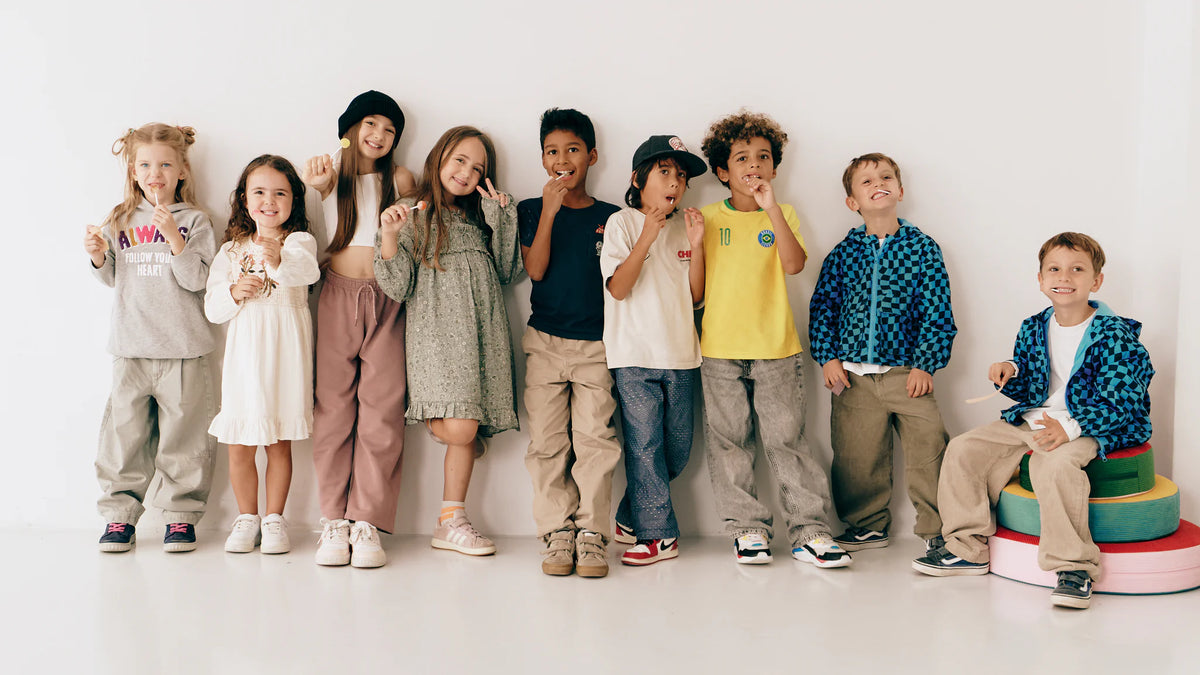 Eine Gruppe Kinder steht nebeneinander vor einer weißen Wand