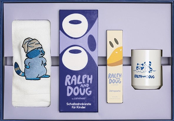 Geöffnete Bundle Box: Handtuch, Schallzahnbürste RALPH, Zahnpasta DOUG und Zahnputzbecher im Fach