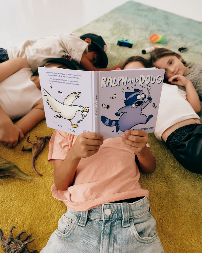 Kinder liegen auf dem Teppich und lesen das Buch